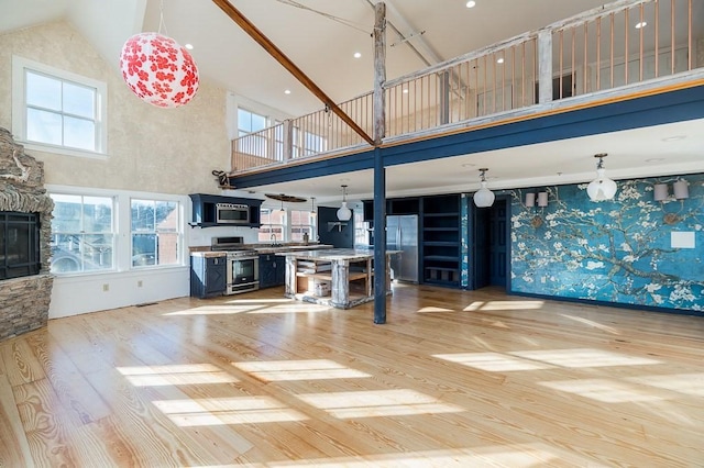 living room featuring a stone fireplace, high vaulted ceiling, and wood finished floors