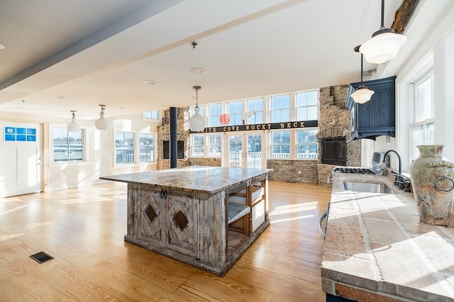 kitchen featuring open floor plan, light wood-style flooring, visible vents, and a sink