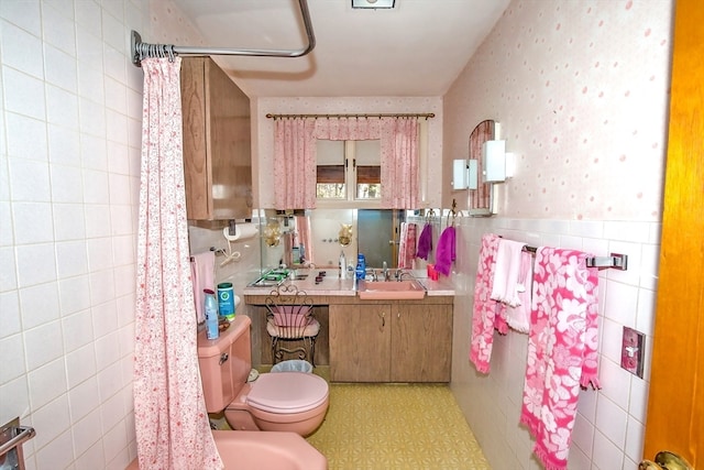 bathroom with walk in shower, toilet, tile walls, and sink