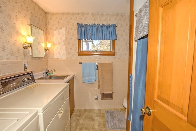 laundry area with washing machine and clothes dryer, sink, and tile walls