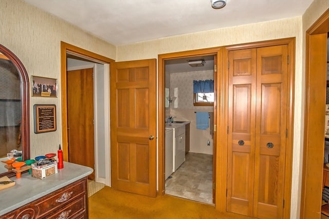 hall with sink, independent washer and dryer, and light carpet