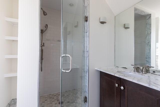 bathroom featuring vanity, lofted ceiling, and a shower with door