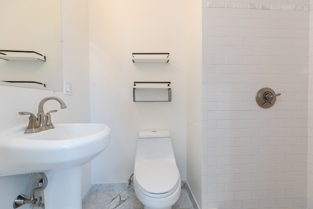 bathroom featuring tiled shower, sink, and toilet