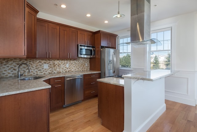 kitchen with island exhaust hood, light hardwood / wood-style flooring, stainless steel appliances, sink, and decorative light fixtures