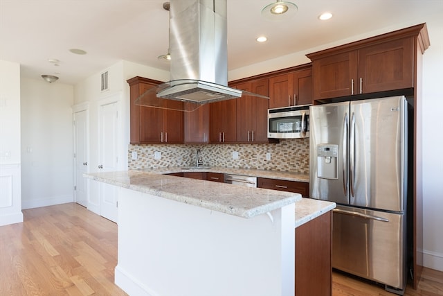 kitchen featuring tasteful backsplash, appliances with stainless steel finishes, light wood-type flooring, island exhaust hood, and light stone counters