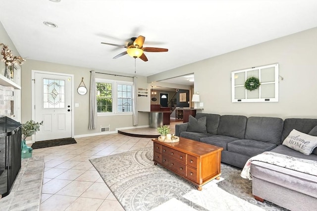 living area featuring baseboards, ceiling fan, visible vents, and light tile patterned floors