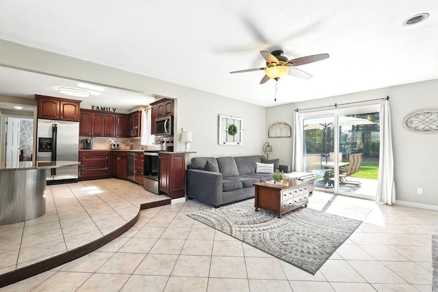 living area with baseboards, ceiling fan, and light tile patterned floors