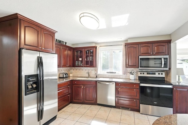 kitchen with a sink, appliances with stainless steel finishes, tasteful backsplash, and light tile patterned floors