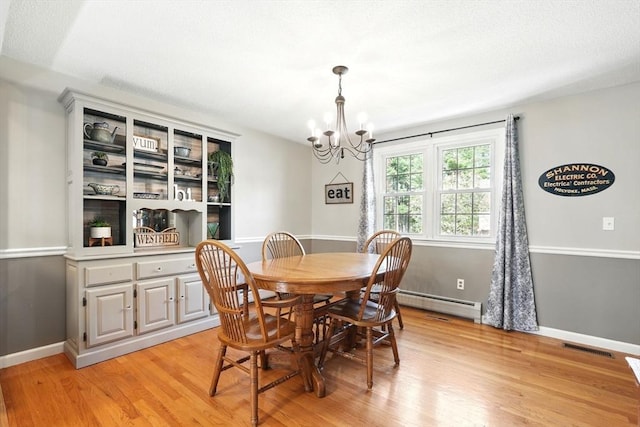 dining room with an inviting chandelier, baseboard heating, visible vents, and light wood-type flooring