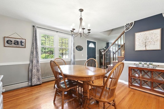 dining area featuring light wood-style floors, stairs, and a chandelier
