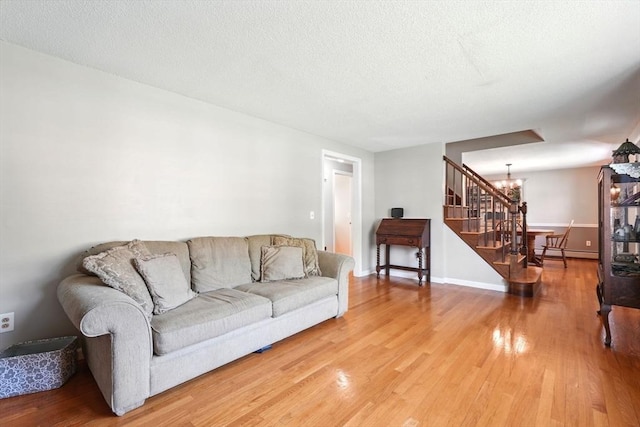 living room featuring stairway, an inviting chandelier, a baseboard heating unit, and wood finished floors