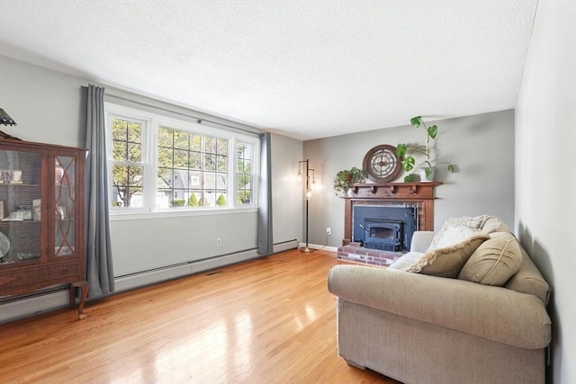living area with a textured ceiling, a brick fireplace, and light wood-style flooring