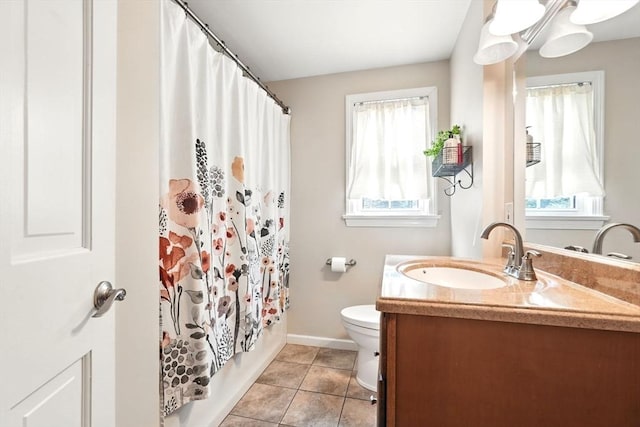 bathroom with vanity, baseboards, a healthy amount of sunlight, and toilet