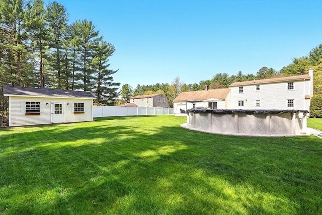 view of yard with an outdoor structure, fence, and a covered pool