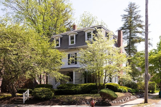 view of front of house featuring mansard roof and a chimney