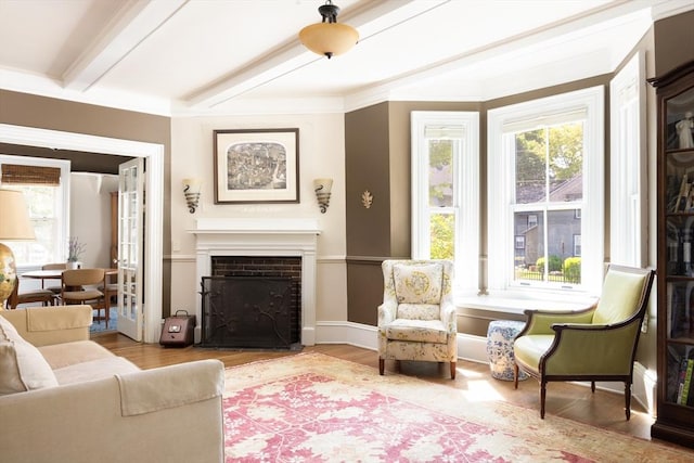 living room with plenty of natural light, beam ceiling, a fireplace with flush hearth, and wood finished floors