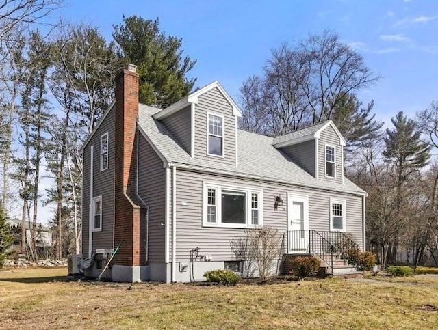 cape cod-style house with roof with shingles, a chimney, and a front lawn