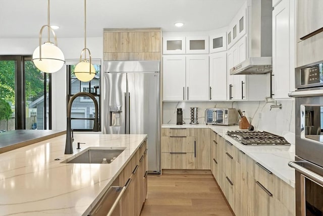 19 Shirley Rd, Medford, MA 02155 - kitchen featuring wall chimney range hood, appliances with stainless steel finishes, light wood-style floors, light stone countertops, and recessed lighting