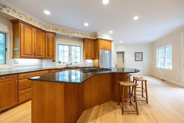 83 High Ridge Rd, Boxford, MA 01921 - kitchen with appliances with stainless steel finishes, healthy amount of natural light, light wood finished floors, brown cabinets, and ornamental molding