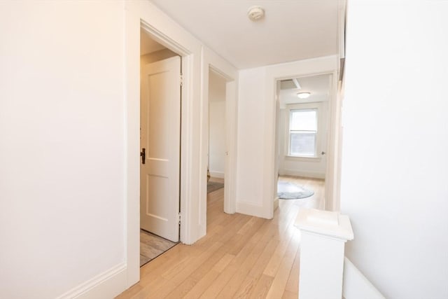 corridor featuring baseboards and light wood finished floors