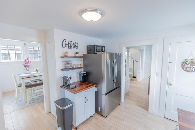 kitchen featuring open shelves, freestanding refrigerator, wooden counters, and light wood-type flooring