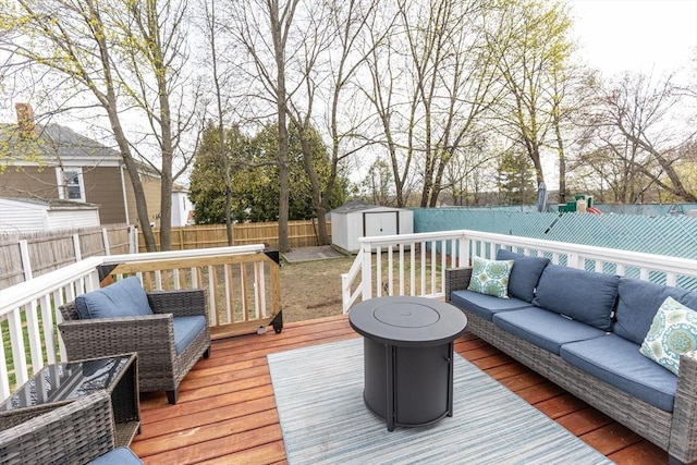 deck featuring a storage shed, an outdoor living space, an outbuilding, and a fenced backyard