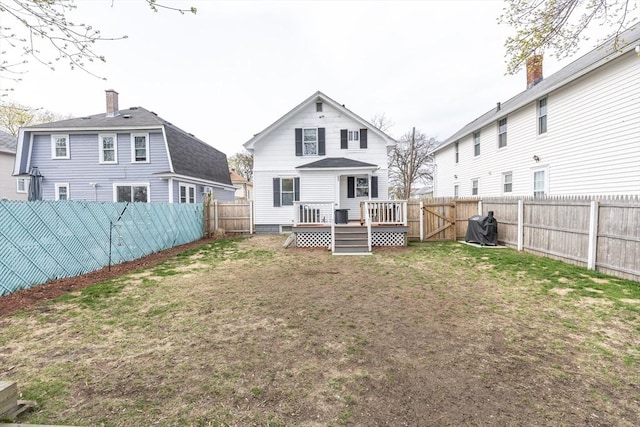 rear view of house featuring a lawn, a deck, and a fenced backyard