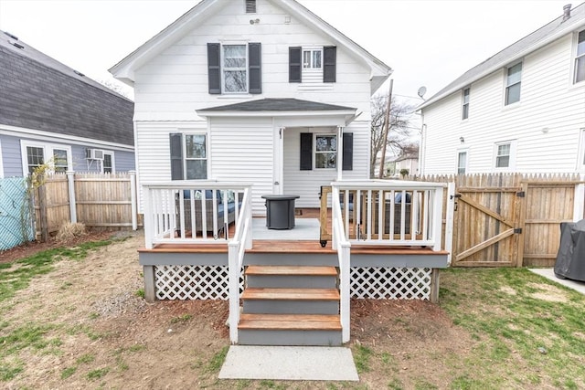 rear view of house with a fenced backyard, a gate, and a wooden deck