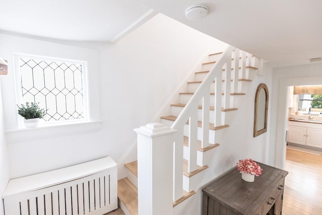 stairs featuring radiator heating unit and wood finished floors
