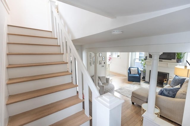 stairway with lofted ceiling with beams, wood finished floors, and a fireplace