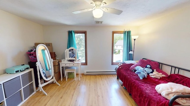 bedroom with wood finished floors, ceiling fan, and baseboard heating