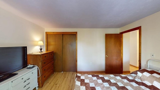 bedroom with light wood-type flooring, baseboards, and a closet