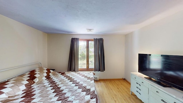 bedroom with light wood-type flooring and baseboards