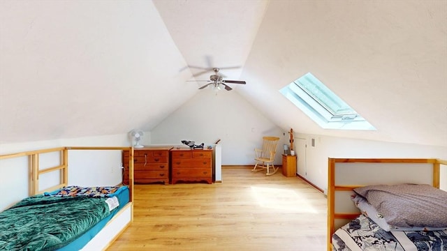 bedroom with a skylight, light wood finished floors, lofted ceiling, and a ceiling fan