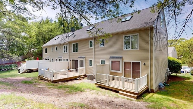 rear view of property with cooling unit, a wooden deck, and a shingled roof
