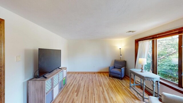living area featuring healthy amount of natural light, light wood-type flooring, and baseboards