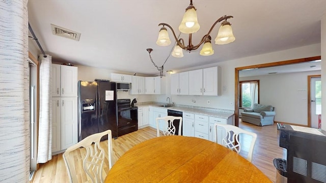kitchen featuring black appliances, a sink, light wood-type flooring, light countertops, and white cabinetry