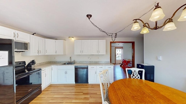 kitchen featuring black appliances, a sink, white cabinets, and light wood finished floors