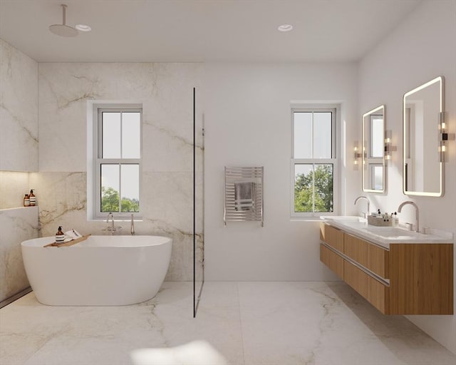 full bathroom with marble finish floor, double vanity, recessed lighting, a freestanding bath, and a sink