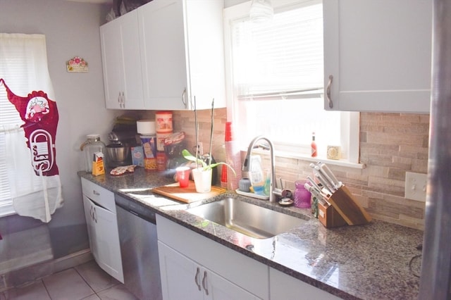 kitchen with white cabinets, sink, tasteful backsplash, stainless steel dishwasher, and dark stone countertops