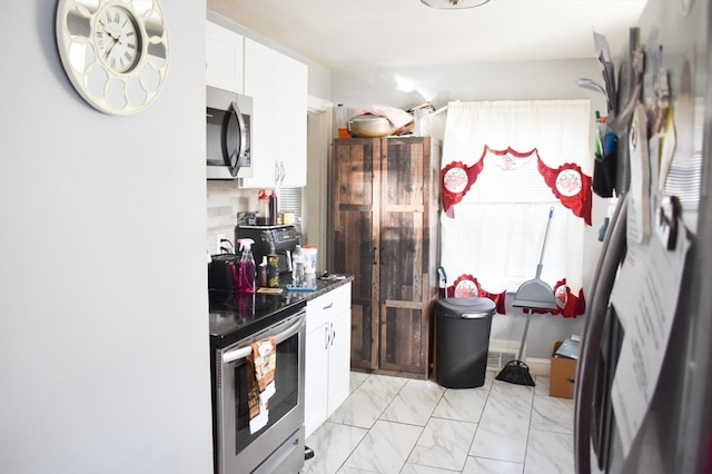 kitchen featuring white cabinets, decorative backsplash, and stainless steel appliances