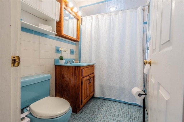 bathroom with toilet, a shower with curtain, tile patterned flooring, vanity, and tile walls