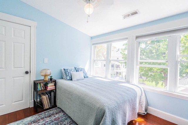 bedroom with wood finished floors, multiple windows, baseboards, and ceiling fan