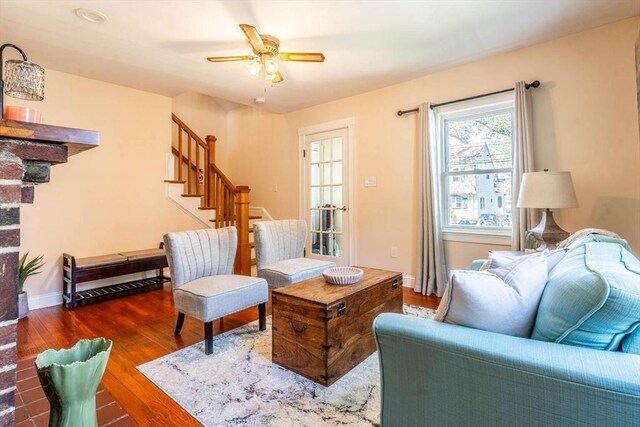 living area with stairs, wood finished floors, a ceiling fan, and baseboards