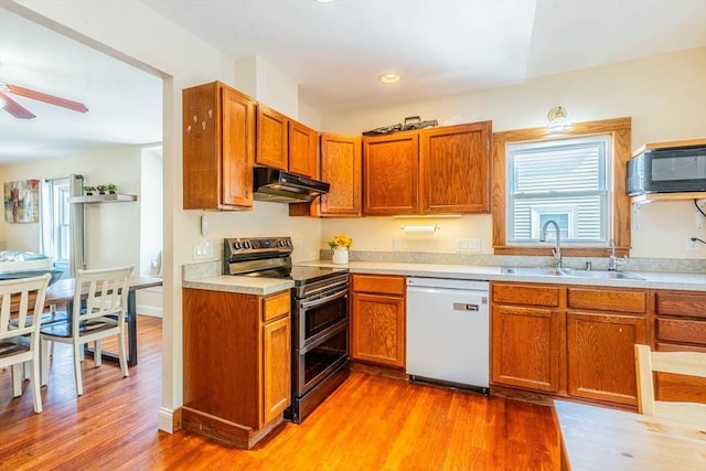 kitchen featuring dishwasher, double oven range, under cabinet range hood, a sink, and black microwave