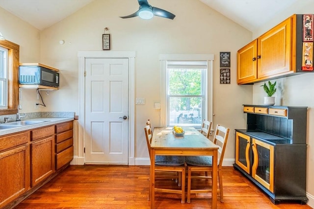 dining space with lofted ceiling, wood finished floors, a ceiling fan, and baseboards