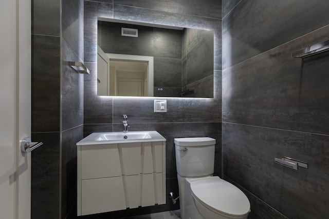 bathroom with vanity, toilet, and tile walls