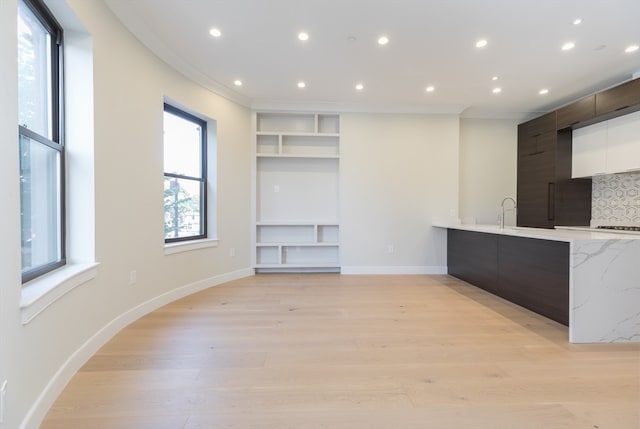 unfurnished living room with crown molding and light wood-type flooring