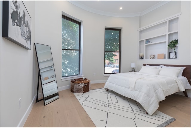 bedroom with crown molding and light wood-type flooring