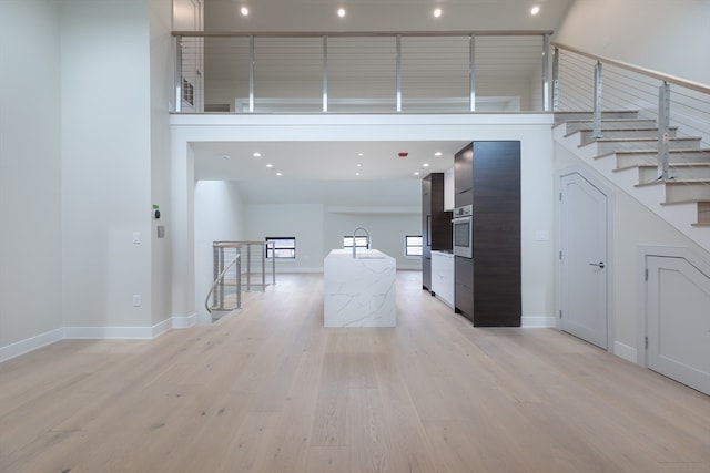 corridor featuring a high ceiling and light wood-type flooring